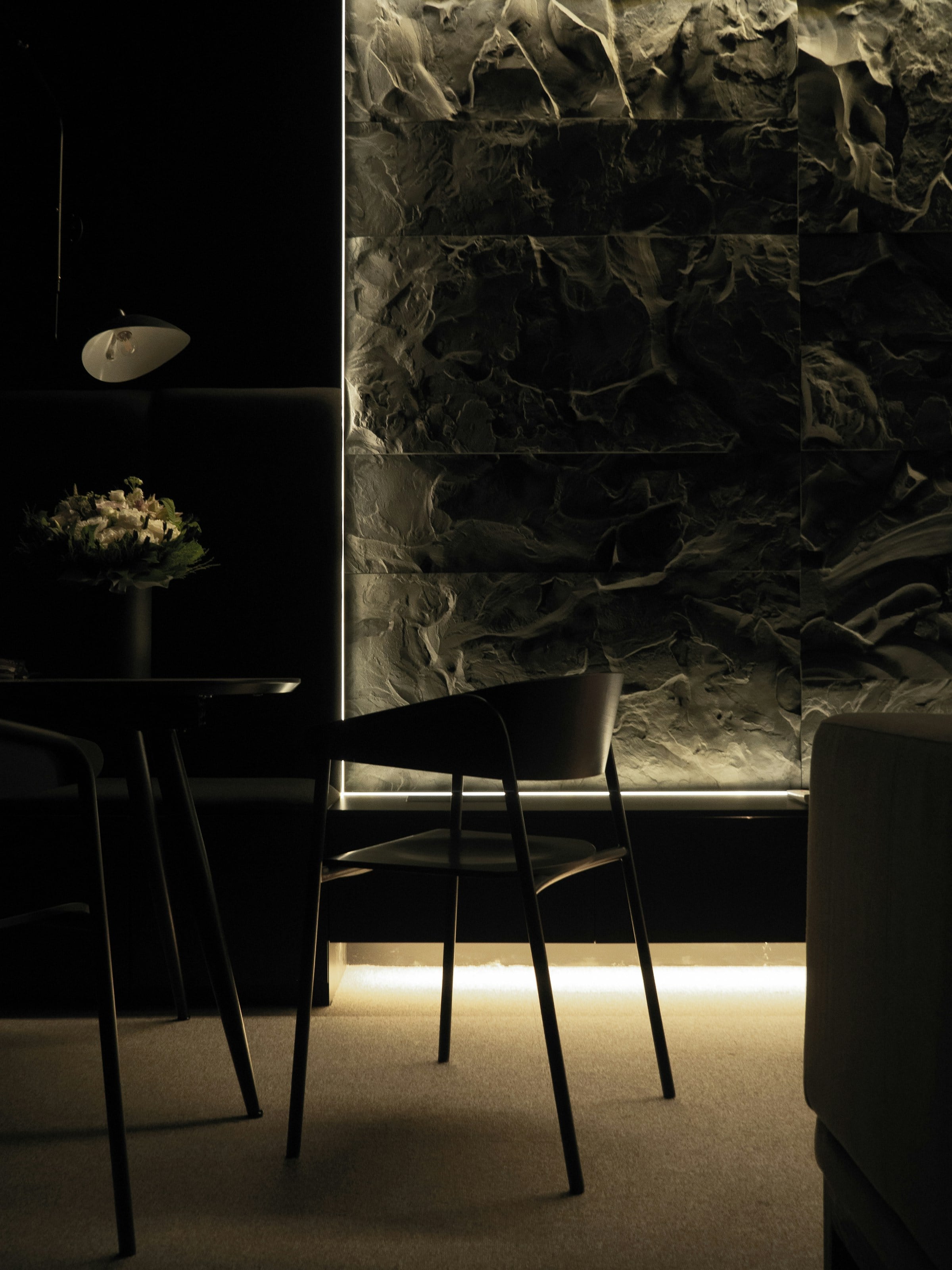 A dark sitting room with warm window light streaming across a marble statue and period seating.